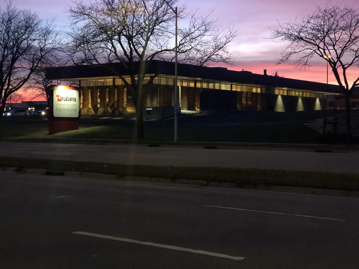 The Rubin's West Side store at dusk, its red roofline and lit sign framed by bare trees
